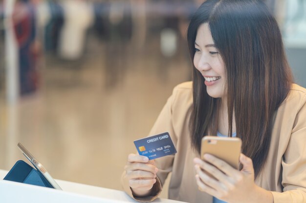 Mujer asiática con tarjeta de crédito con teléfono móvil para compras online en grandes almacenes