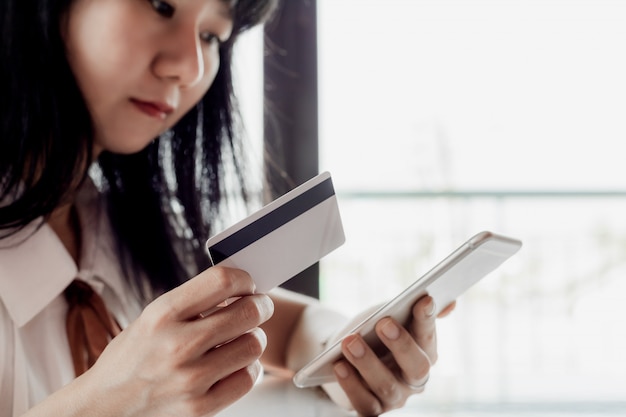 Mujer asiática con una tarjeta de crédito y uso de teléfonos inteligentes