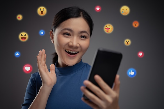 Mujer asiática con teléfono inteligente para redes sociales con burbuja de emoticonos. Aislado