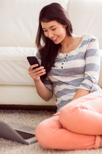 Mujer asiática con teléfono en el piso