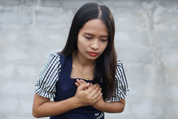 Mujer asiática tiene dolor en el pecho debido a una enfermedad cardíaca