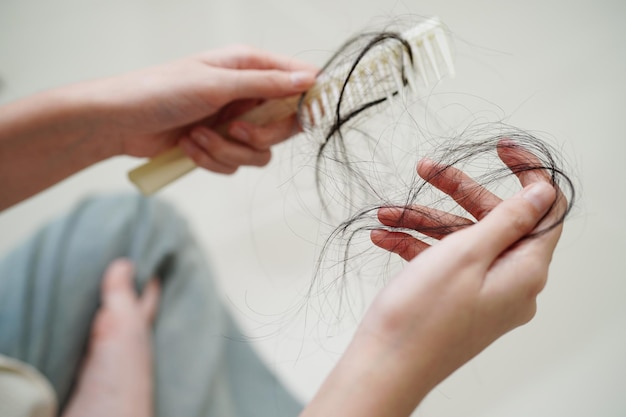 Mujer asiática tiene problemas con la pérdida de cabello largo en su mano