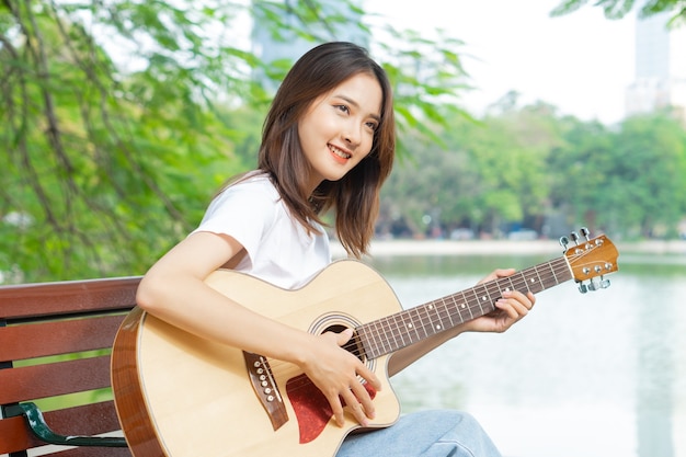 Mujer asiática, tocar la guitarra, en la calle
