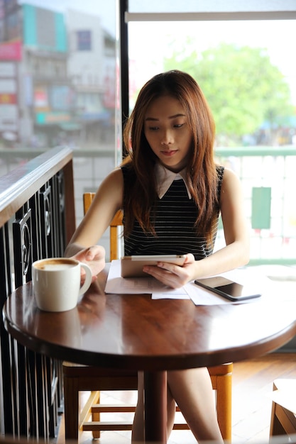 Mujer asiática tomando café con tableta