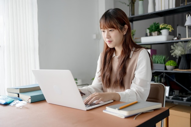 Mujer asiática trabajando con una computadora portátil en la sala de estar