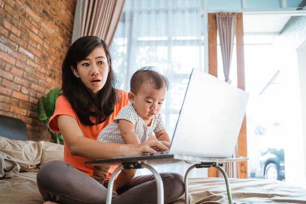 Mujer asiática trabajando mientras cuida niños