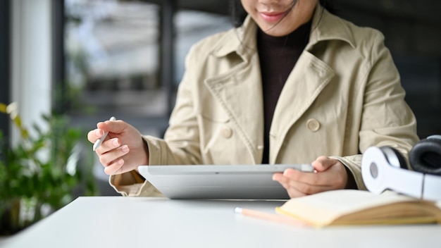 Mujer asiática trabajando remotamente en la cafetería o en el espacio de coworking usando su tableta digital