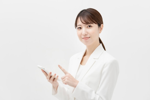 Mujer asiática en traje blanco con un teléfono inteligente