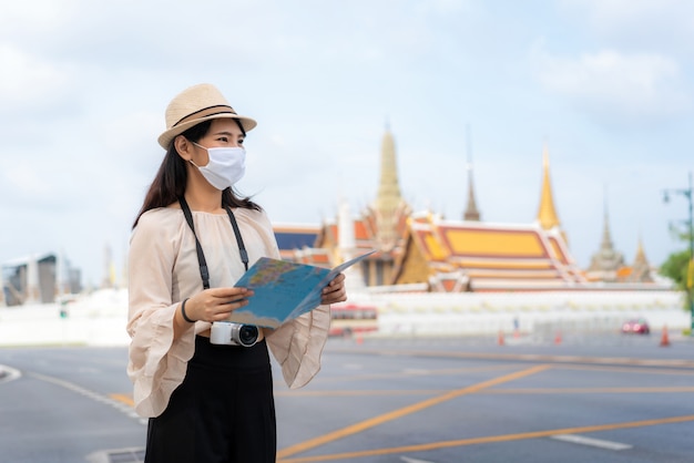 Mujer asiática turistas felices de viajar con máscara