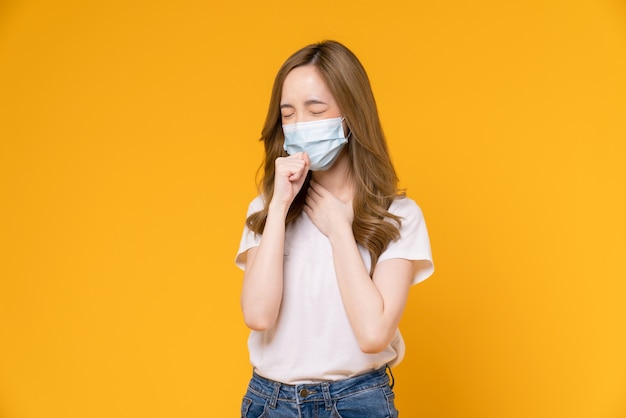 La mujer asiática usa máscaras para proteger la enfermedad sobre fondo amarillo.