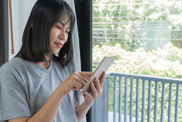 Mujer asiática usa tableta revisa correo electrónico chica asiática mira móvil mira redes sociales
