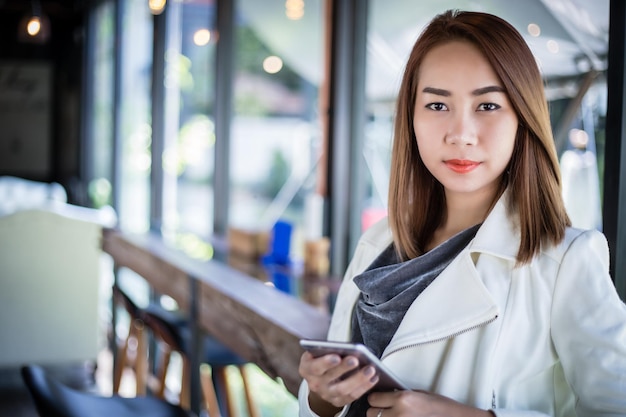 Mujer asiática usando el teléfono para comprar en línea y llamando con el teléfono celular en la cafetería