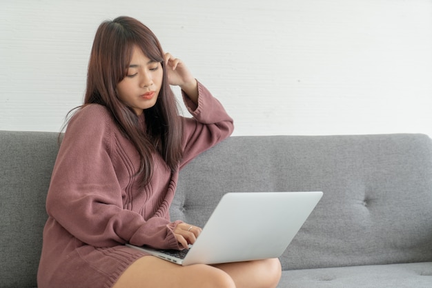 Mujer asiática, usar la computadora portátil, en, sofá, en, sala