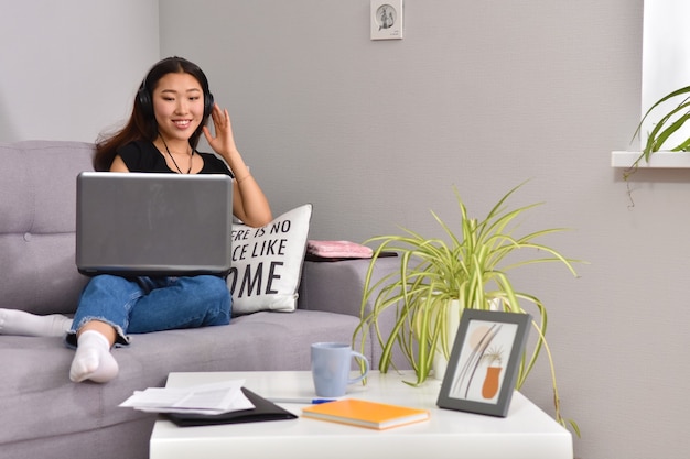 Mujer asiática, usar la computadora portátil, en, sofá