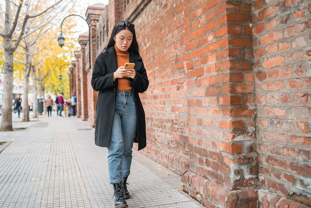 Mujer asiática utilizando su teléfono móvil.