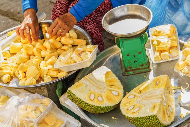 Mujer asiática vendiendo carne de fruta durián fresca recién limpiada y empaquetada en la calle en Hoi An, Vietnam.