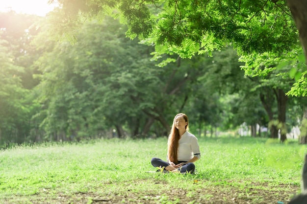 Mujer asiática con un vestido blanco meditando en el parque