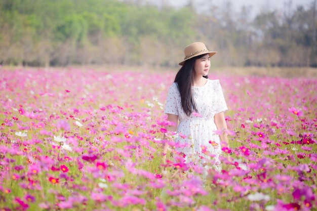 Mujer asiática con vestido blanco relajándose en el campo de flores de Margaret Aster en el jardín