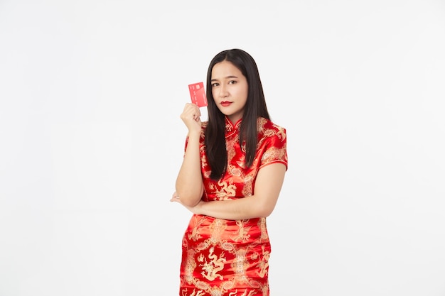 Mujer asiática con vestido qipao oriental mostrando tarjeta de crédito roja en mano en superficie de estudio aislado gris claro