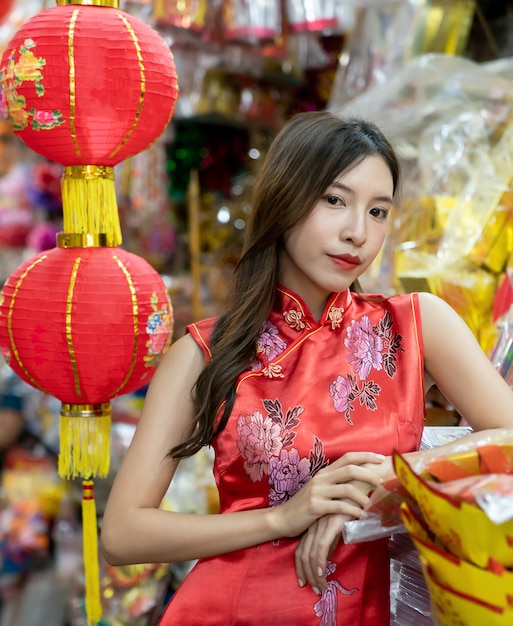 Mujer asiática con vestido rojo Cheongsam de compras en el mercado para el año nuevo chino.