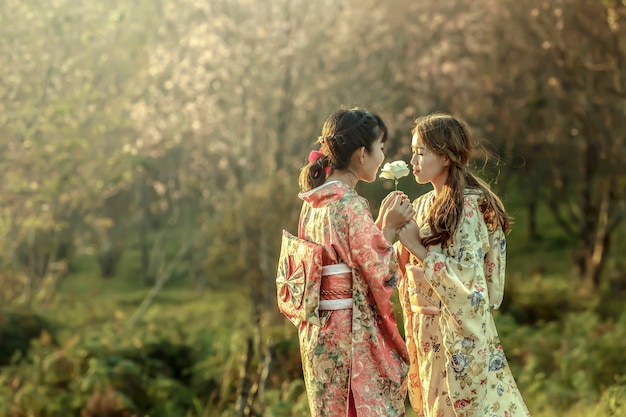 Mujer asiática con vestido tradicional camaleón en el jardín de sakura, Tailandia