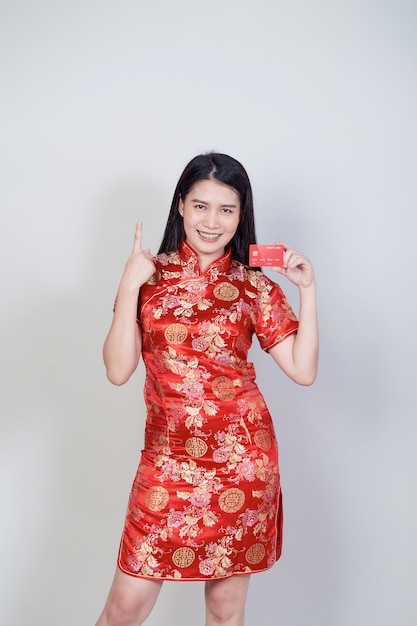 Foto mujer asiática con vestido tradicional cheongsam qipao mostrando tarjeta de crédito para conceptos de compras del año nuevo chino.