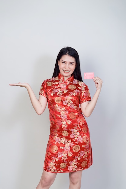 Mujer asiática con vestido tradicional cheongsam qipao mostrando tarjeta de crédito para conceptos de compras del año nuevo chino.