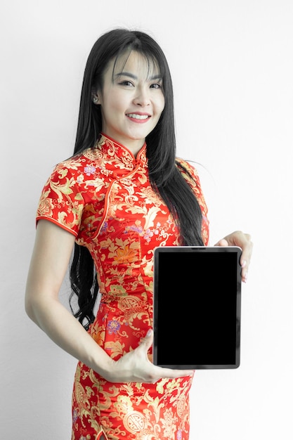 Mujer asiática con vestido tradicional cheongsam qipao que muestra la presentación de una tableta digital sobre fondo blanco Compras de año nuevo chino Compras en línea Mujer china con vestido tradicional