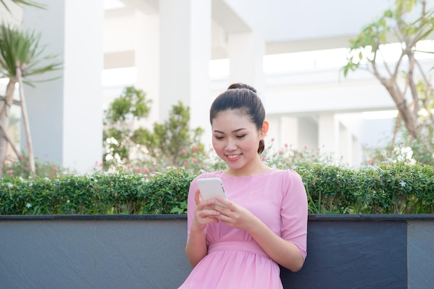 Mujer asiática con vestido tradicional enviando mensajes de texto en un teléfono inteligente