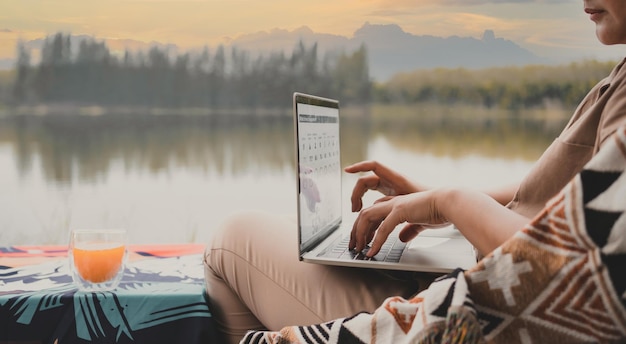 Mujer asiática viaja y acampa sola. Empresaria trabajando en línea y relajándose durante la actividad al aire libre del viaje.