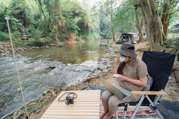 Mujer asiática viaja y acampa sola. Empresaria trabajando en línea y relajándose durante la actividad al aire libre del viaje.