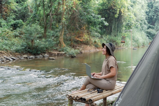 Mujer asiática viaja y acampa sola. Empresaria trabajando en línea y relajándose durante la actividad al aire libre del viaje.