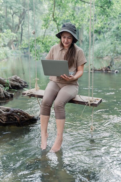 Mujer asiática viaja y acampa sola. Empresaria trabajando en línea y relajándose durante la actividad al aire libre del viaje.