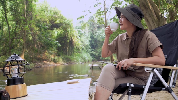 Mujer asiática viaja y acampa sola. Empresaria trabajando en línea y relajándose durante la actividad al aire libre del viaje.