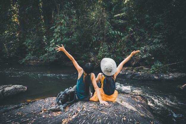 Mujer asiática viajes mirar el río y la pequeña cascada en la montaña, concepto de verano relajarse libertad naturaleza al aire libre vacaciones vacaciones viaje