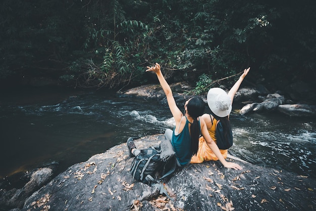 Mujer asiática viajes mirar el río y la pequeña cascada en la montaña, concepto de verano relajarse libertad naturaleza al aire libre vacaciones vacaciones viaje