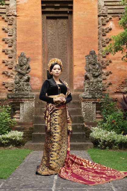 Mujer asiática vistiendo kebaya balinesa y tela tejida contra el templo