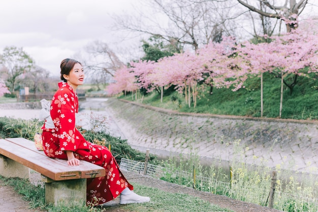 Foto mujer asiática vistiendo kimono con flores de cerezo, sakura en japón.