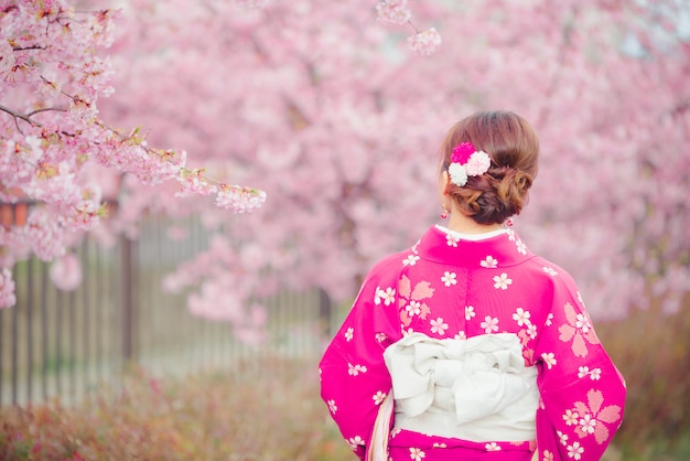 Mujer asiática vistiendo kimono con flores de cerezo, sakura en Japón.