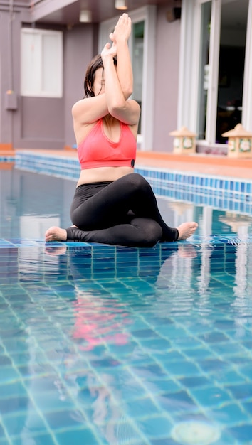 Mujer asiática yoga respiración y meditación solo en la piscina en casa. Ejercicio al aire libre y entrenamiento para la salud y el bienestar.