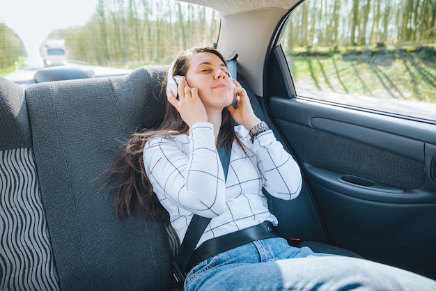 Mujer en el asiento trasero del coche. concepto de viaje en coche. listado de música con auriculares.