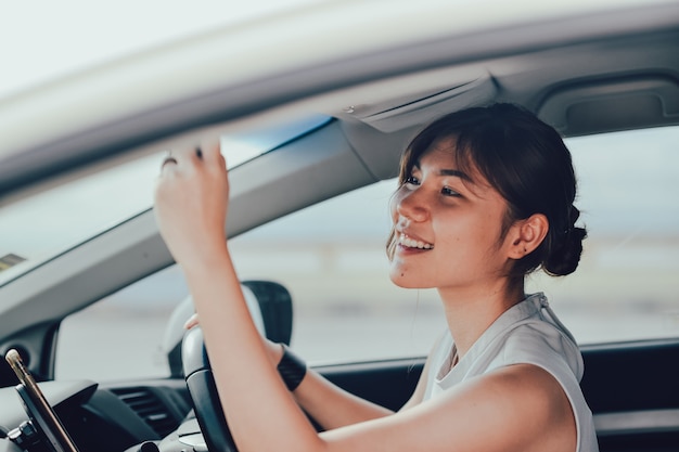 Mujer asisn relajada sonriendo mirando en el espejo retrovisor. emplazamiento en el coche. concepto de estilo de vida y personas.