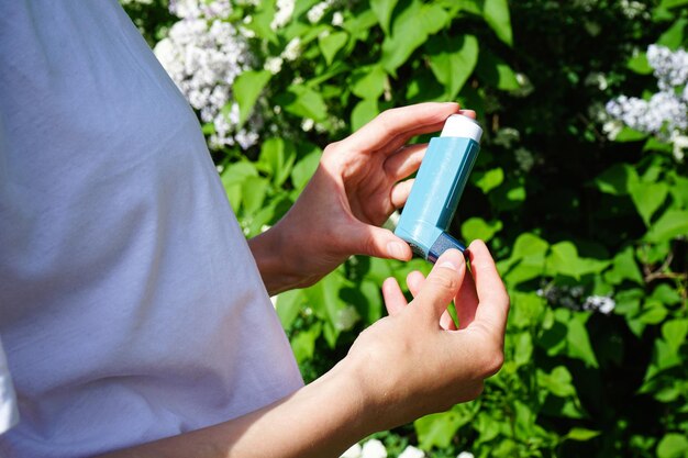 Mujer asmática usando inhalador de un ataque de asma al aire libre closeup