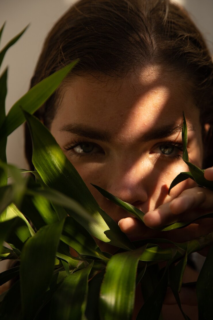 Foto mujer asoma detrás de una palmera