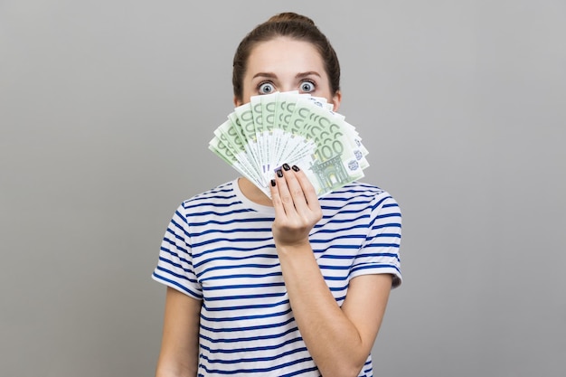 Una mujer asomando los billetes en euros con una mirada juguetona disfrutando del gran éxito financiero del premio mayor