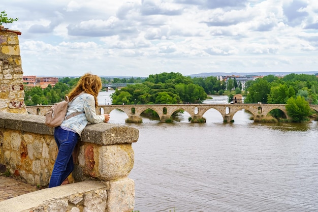Mujer asomándose al río que pasa frente a la ciudad medieval de Zamora