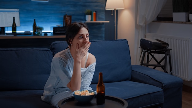 Mujer asombrada mirando la película en la televisión habiendo sorprendido la expresión facial