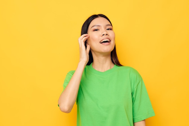 Mujer con aspecto asiático en camisetas verdes gestos con las manos emociones fondo amarillo inalterado