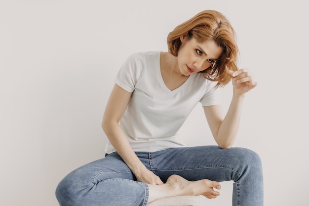 Mujer de aspecto fresco en camiseta blanca y jean relajarse en la habitación de su apartamento.