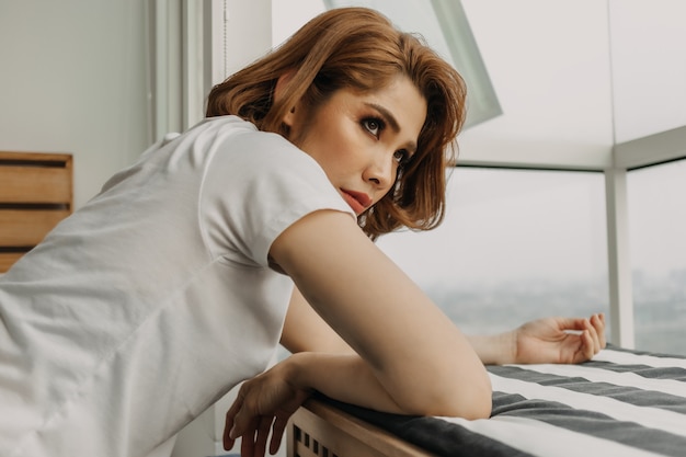 Mujer de aspecto fresco está descansando y mirando la vista desde su apartamento